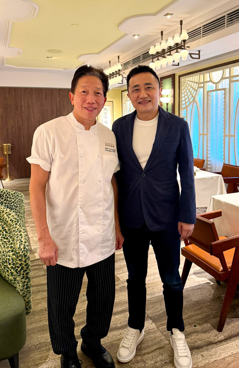 Chef Max Wo Hoi-ming with guest in elegant restaurant setting.