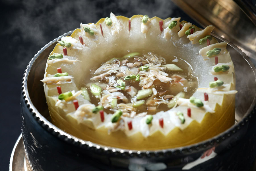 Traditional Chinese hot pot with vegetables and meat in a festive setting.