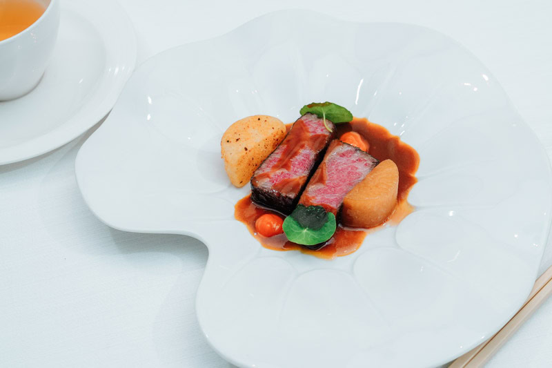 Gourmet Chinese Cuisine Presentation Elegant Chinese dish with beef, vegetables, and sauce on a white plate.
