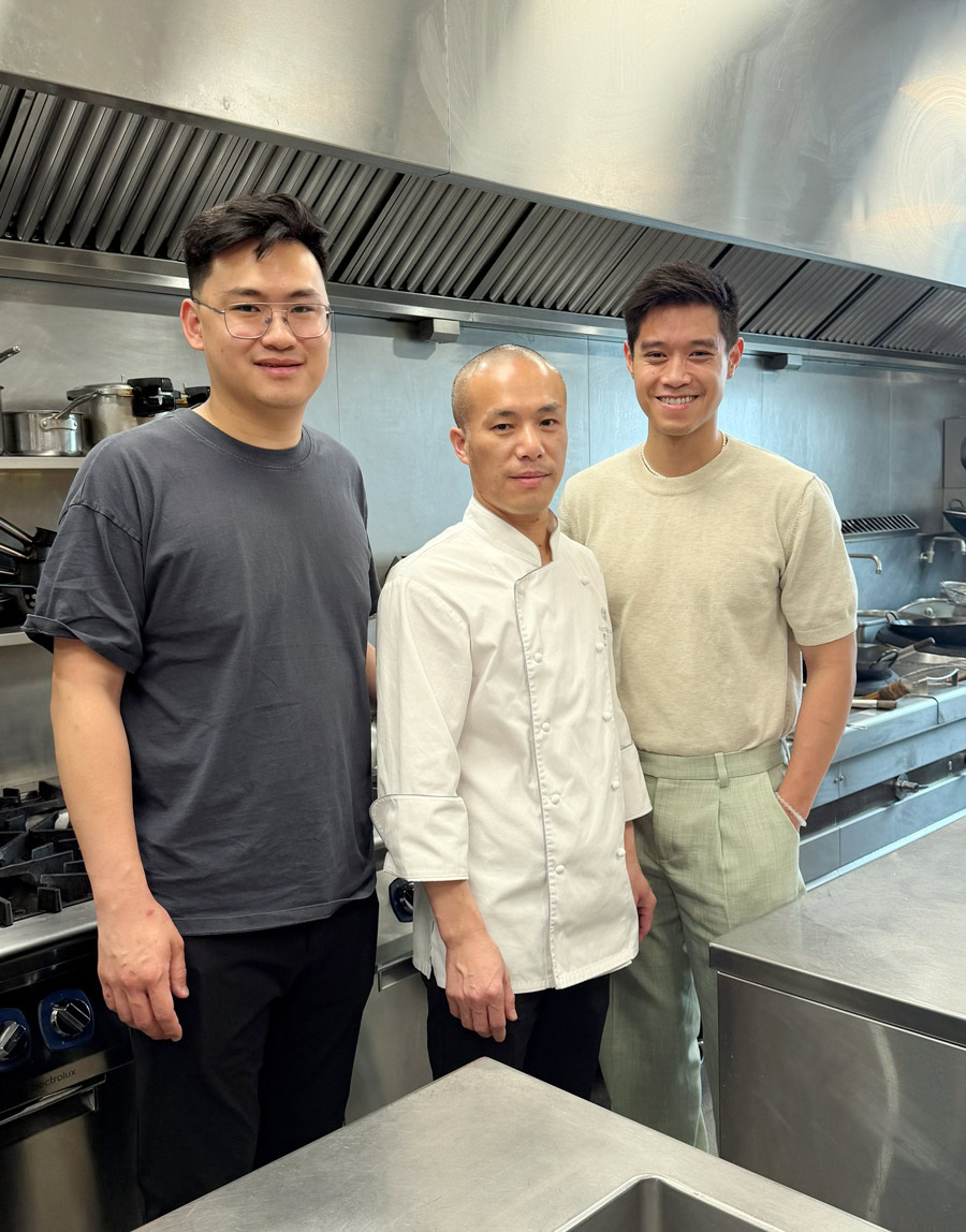 Chinese Restaurant Awards Celebration Three chefs in a professional kitchen celebrating culinary excellence.